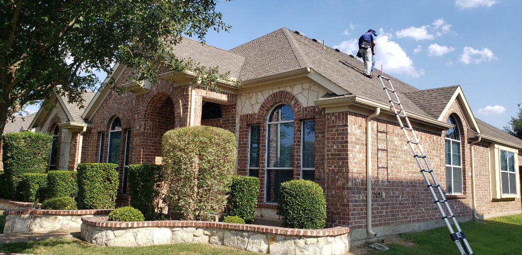 Roofer on a ladder inspecting a roof